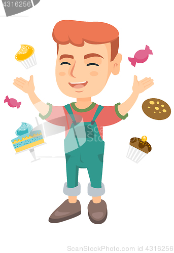 Image of Happy caucasian boy standing among lots of sweets.