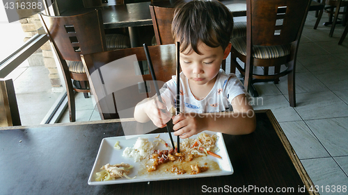 Image of Cute Young Chinese and Caucasian Boy Learning To Use Chopsticks 