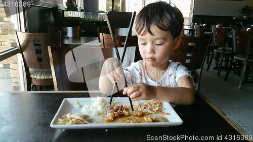 Image of Cute Young Chinese and Caucasian Boy Learning To Use Chopsticks 