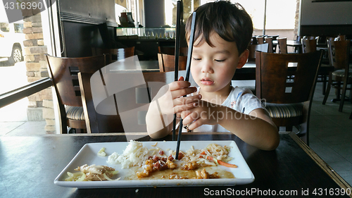 Image of Cute Young Chinese and Caucasian Boy Learning To Use Chopsticks 