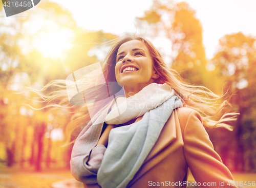 Image of beautiful happy young woman walking in autumn park