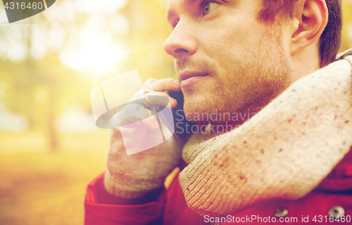 Image of close up of man with smartphone calling in autumn