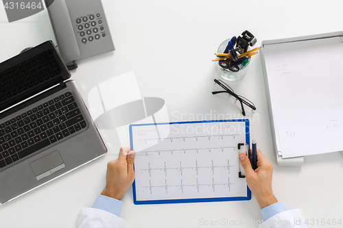 Image of doctor hands with cardiogram and laptop at clinic