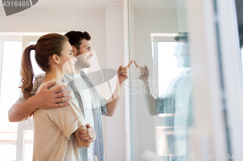 Image of happy couple looking through window at new home