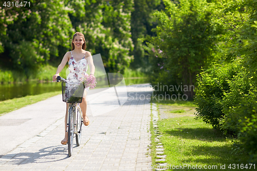 Image of happy woman riding fixie bicycle in summer park