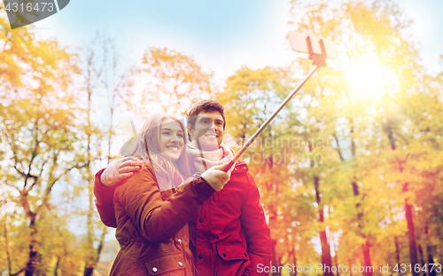 Image of couple taking selfie by smartphone in autumn park