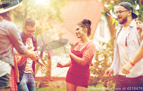 Image of happy friends dancing at summer party in garden