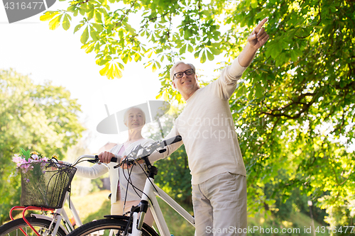 Image of happy senior couple with bicycles at summer park