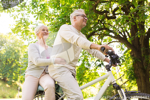 Image of happy senior couple riding on bicycle at park