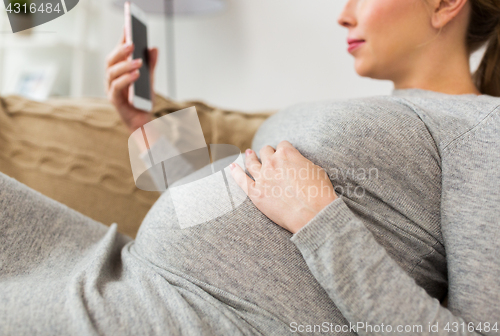 Image of happy pregnant woman with smartphone at home