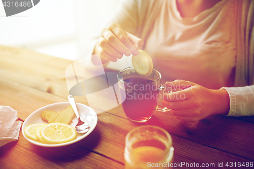 Image of close up of woman adding lemon to tea cup