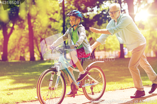 Image of grandfather and boy with bicycle at summer park