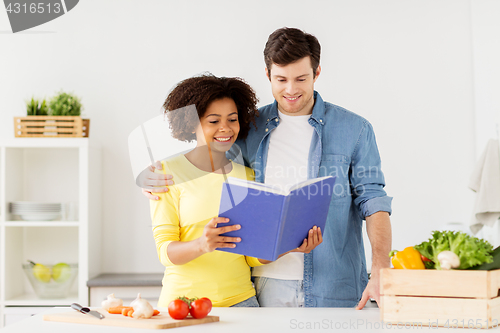 Image of happy couple with cooking book at home kitchen