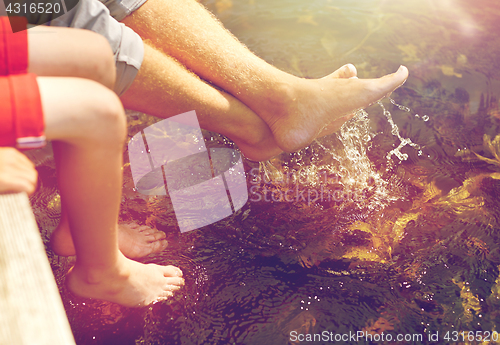 Image of grandfather and grandson sitting on river berth