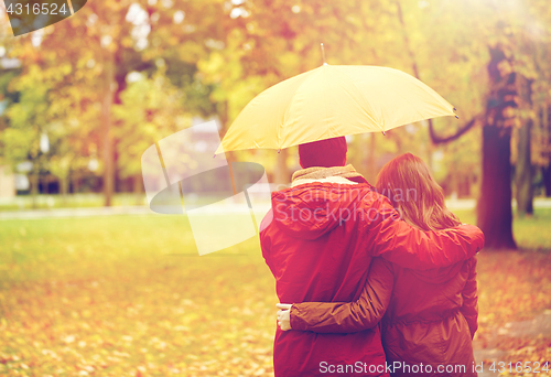 Image of happy couple with umbrella walking in autumn park