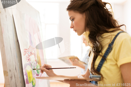 Image of student girl with easel painting at art school