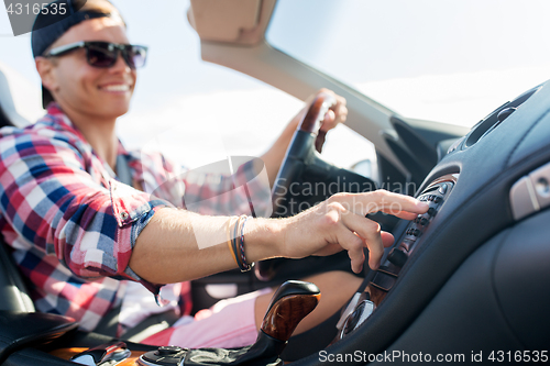 Image of happy young man driving convertible car