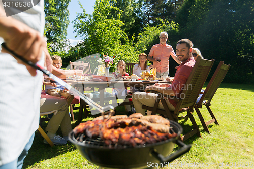 Image of man cooking meat on barbecue grill at summer party