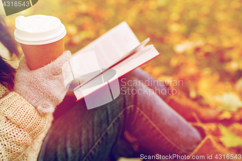 Image of woman with book drinking coffee in autumn park