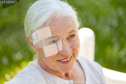 Image of happy senior woman sitting on bench at summer park