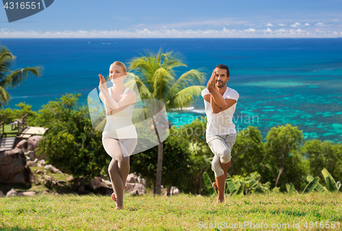 Image of smiling couple making yoga exercises outdoors