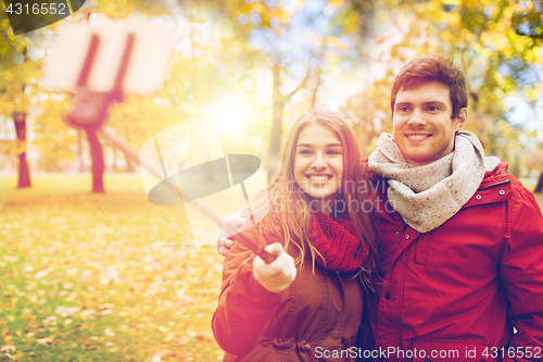 Image of couple taking selfie by smartphone in autumn park