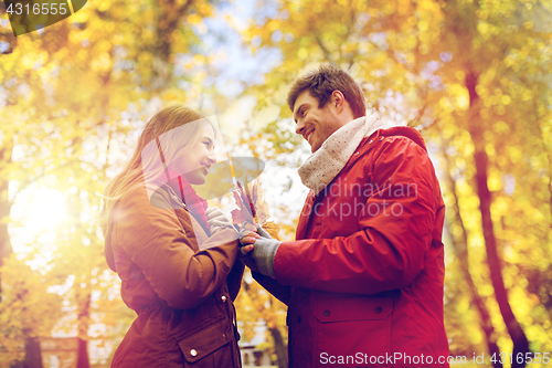 Image of happy couple with maple leaves in autumn park