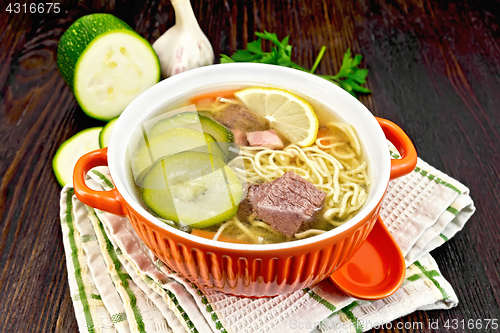 Image of Soup with zucchini and noodles in bowl on board