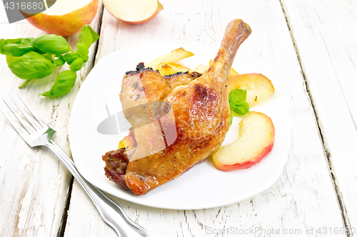 Image of Duck leg with apple in plate on board