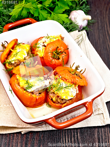 Image of Tomatoes stuffed with rice and meat in brazier on dark board