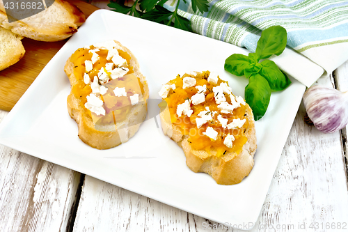 Image of Bruschetta with pumpkin and feta in plate on board