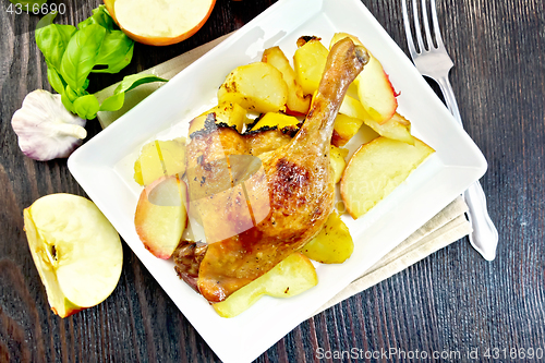 Image of Duck leg with apple and basil in plate on board top