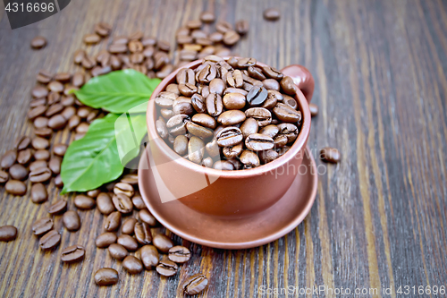 Image of Coffee black grain in cup with leaf on board