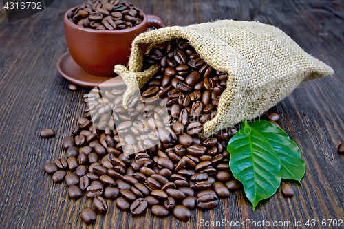Image of Coffee black grains in bag with cup and leaf on board
