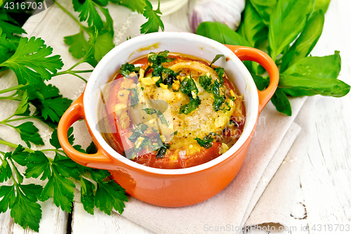 Image of Fish baked with tomato in red pot on towel