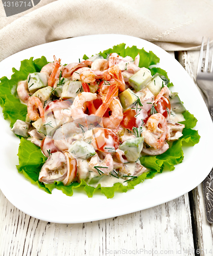 Image of Salad with shrimp and tomato in white plate on light board