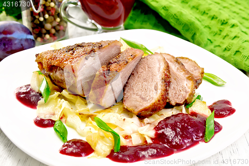 Image of Duck breast with plum sauce and cabbage in plate on board