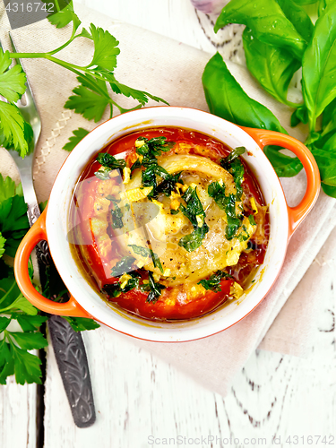 Image of Fish baked with tomato in red pot on napkin top