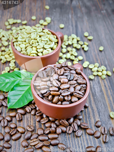 Image of Coffee black and green grains in cups with leaf on dark board