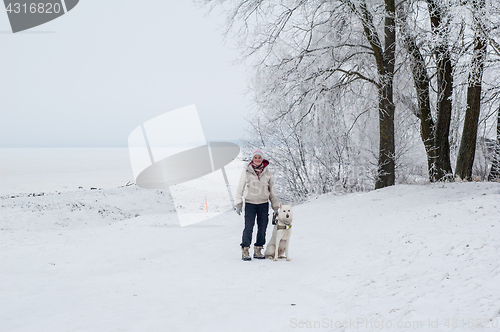 Image of Woman walking with a dog in winter