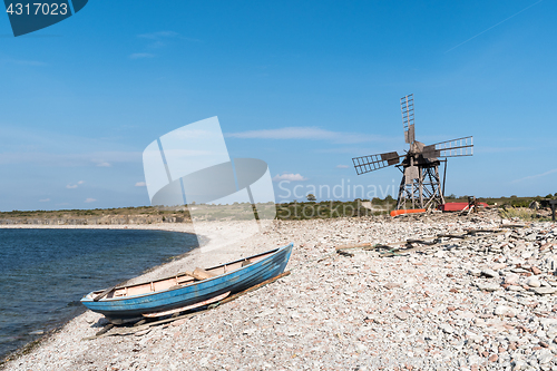 Image of Blue rowing boat and an old windmill by seaside