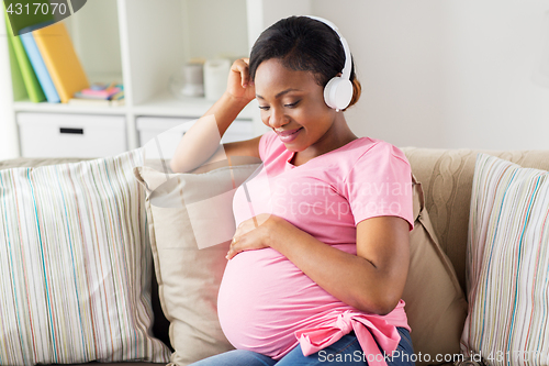 Image of pregnant woman in headphones at home