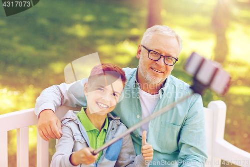 Image of old man and boy taking selfie by smartphone