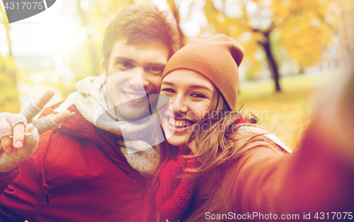 Image of happy young couple taking selfie in autumn park