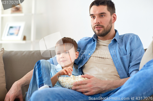 Image of father and son with popcorn watching tv at home