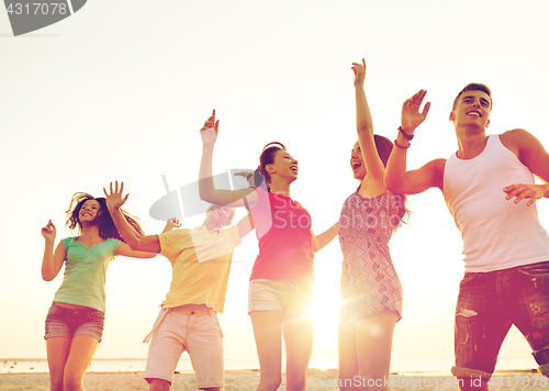 Image of smiling friends dancing on summer beach