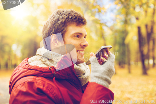 Image of man recording voice on smartphone at autumn park