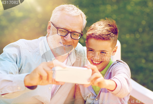 Image of old man and boy taking selfie by smartphone