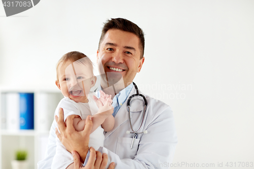 Image of happy doctor or pediatrician with baby at clinic