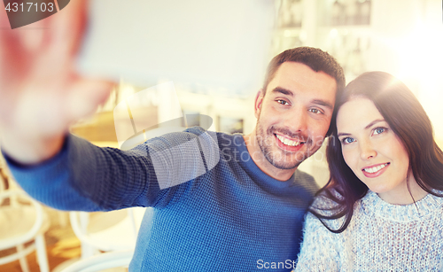 Image of couple taking smartphone selfie at cafe restaurant